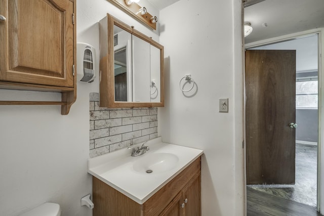 bathroom featuring toilet, backsplash, and vanity