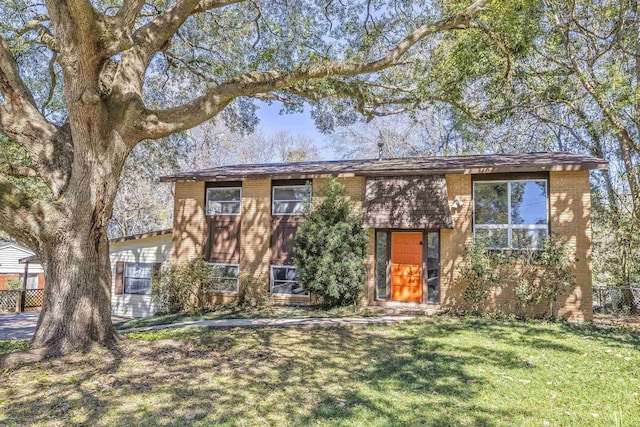 view of front of property with a front yard, brick siding, and fence