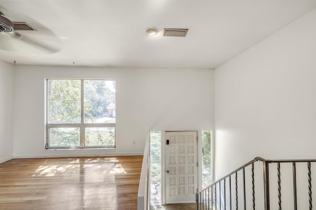 interior space with a ceiling fan, visible vents, baseboards, and wood finished floors