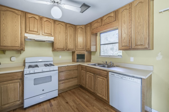 kitchen with white appliances, dark wood-style floors, light countertops, under cabinet range hood, and a sink