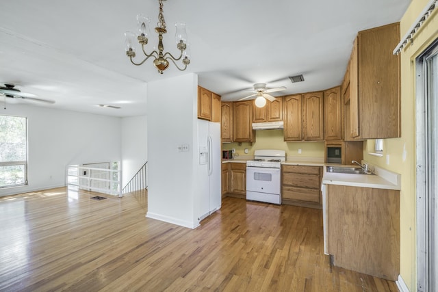 kitchen featuring white appliances, brown cabinets, light wood-type flooring, under cabinet range hood, and a sink