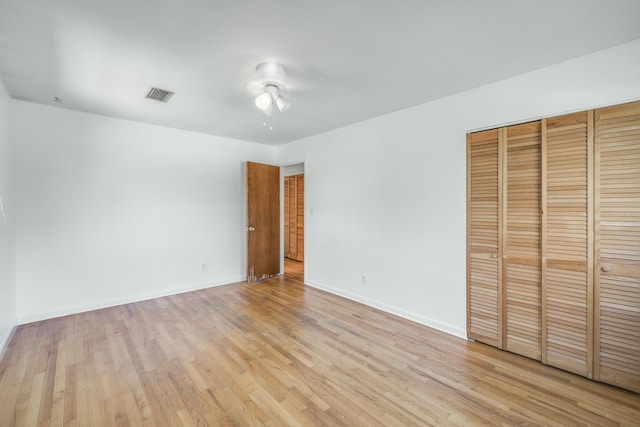 unfurnished bedroom with light wood finished floors, baseboards, visible vents, a ceiling fan, and a closet