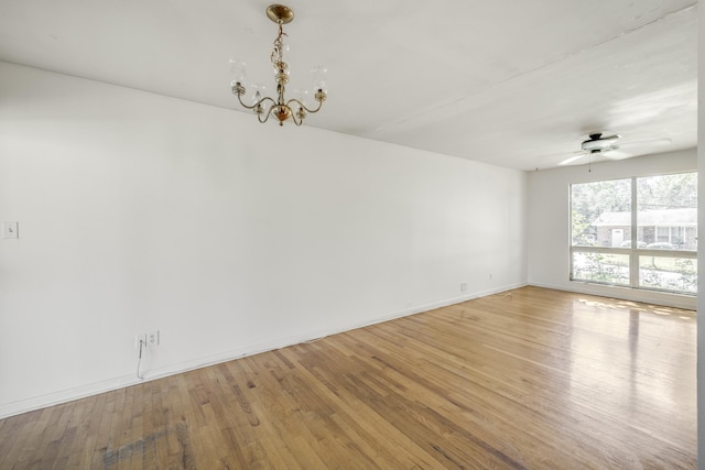 unfurnished room with ceiling fan with notable chandelier, light wood-style flooring, and baseboards