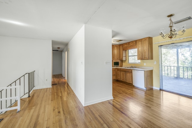 kitchen with baseboards, dishwasher, light countertops, light wood-type flooring, and a sink