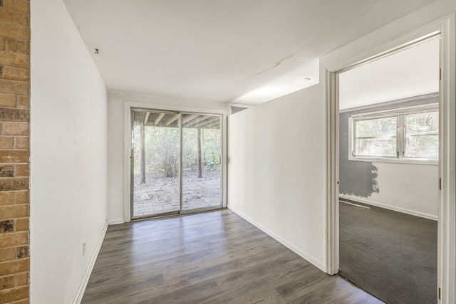 empty room featuring dark wood-type flooring, a wealth of natural light, and baseboards