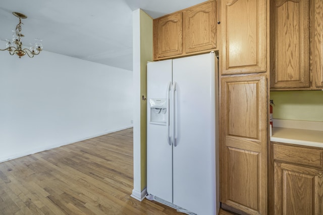 kitchen with white refrigerator with ice dispenser, light countertops, hanging light fixtures, light wood finished floors, and an inviting chandelier