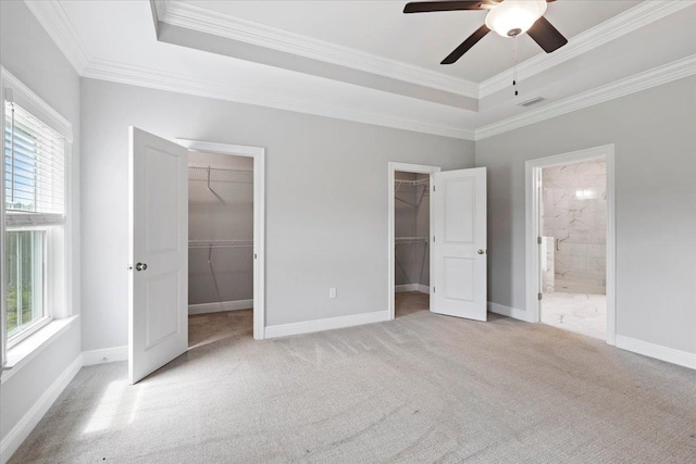 unfurnished bedroom featuring connected bathroom, a walk in closet, multiple windows, and ceiling fan