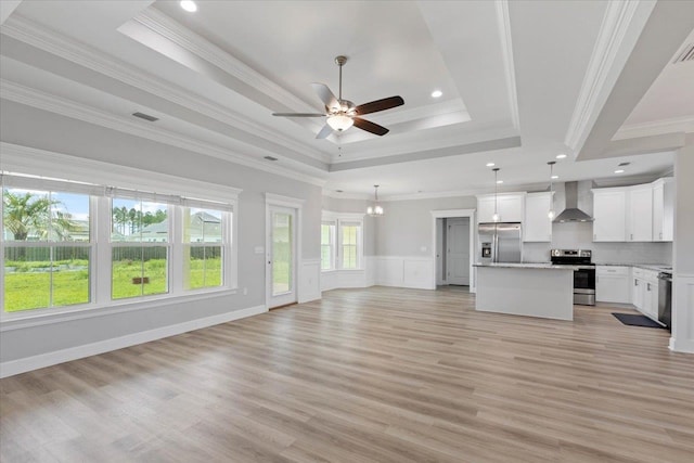 unfurnished living room featuring light wood-type flooring, ceiling fan, crown molding, and a tray ceiling