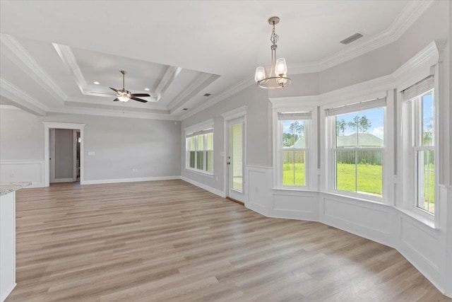 unfurnished living room featuring light wood-type flooring, ceiling fan with notable chandelier, a raised ceiling, and crown molding