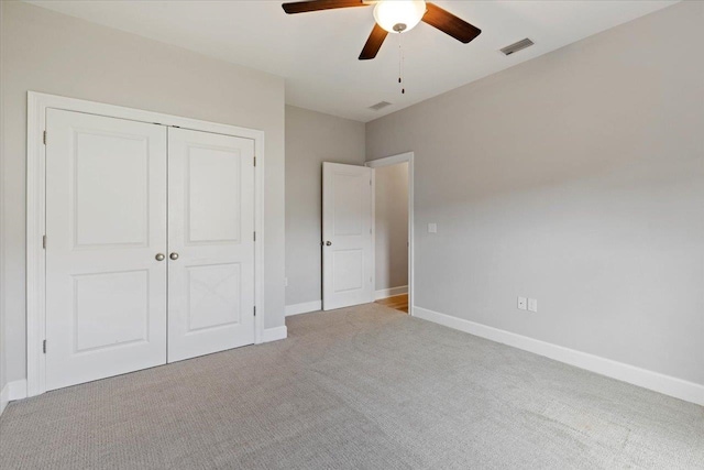 unfurnished bedroom featuring a closet, light colored carpet, and ceiling fan