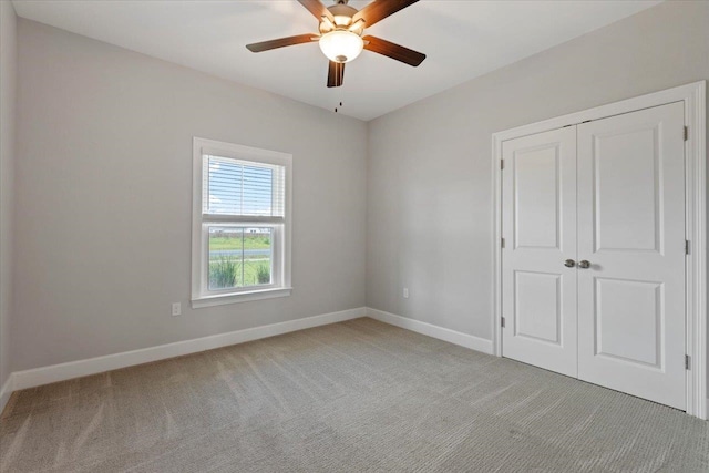 unfurnished bedroom featuring light colored carpet, ceiling fan, and a closet