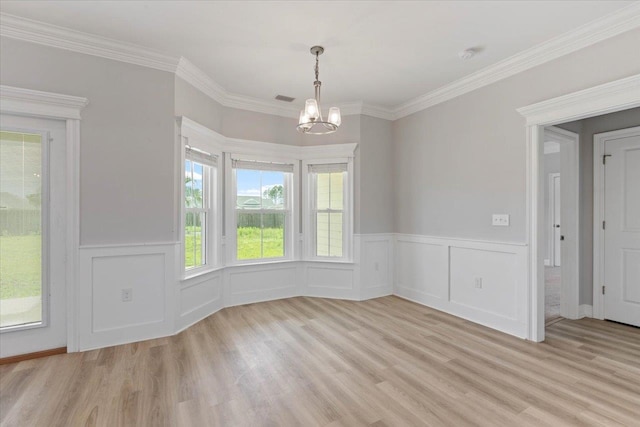 unfurnished dining area featuring ornamental molding, light wood-type flooring, and an inviting chandelier