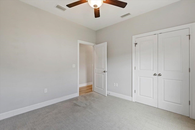 unfurnished bedroom featuring a closet, light colored carpet, and ceiling fan