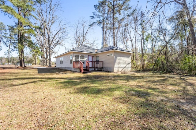 back of property featuring a wooden deck and a lawn