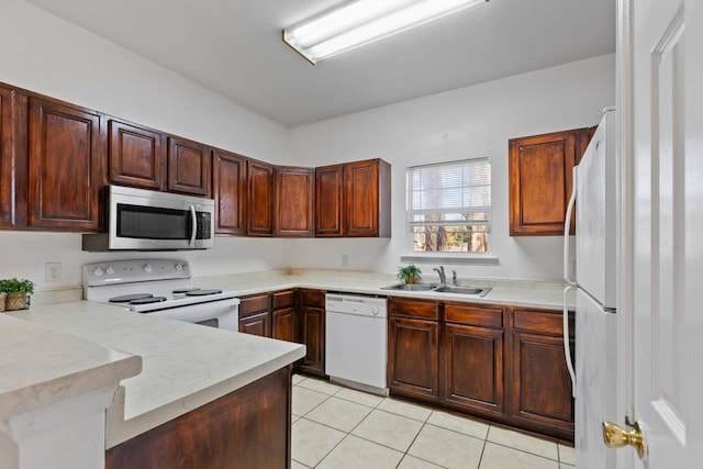 kitchen with light tile patterned flooring, white appliances, kitchen peninsula, and sink