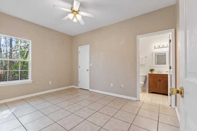 unfurnished bedroom with ceiling fan, ensuite bath, sink, and light tile patterned floors