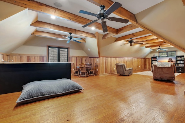 bedroom featuring light wood-type flooring, wainscoting, and lofted ceiling with beams