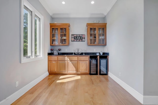 bar featuring crown molding, light wood-style flooring, wet bar, beverage cooler, and baseboards