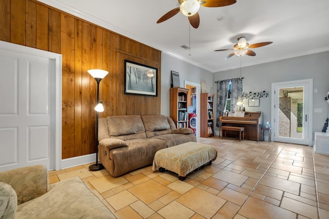 living area featuring ceiling fan, wood walls, visible vents, and crown molding