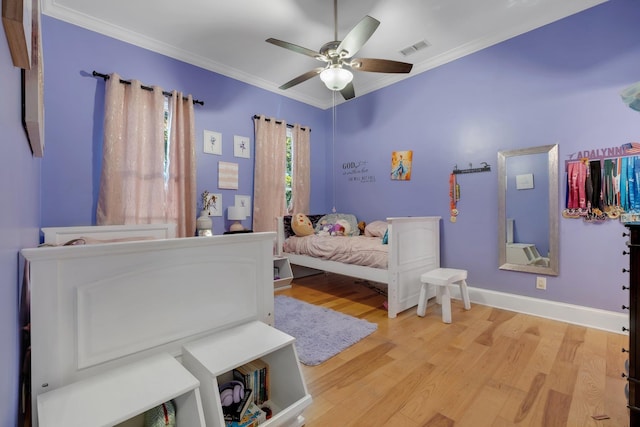 bedroom with baseboards, light wood finished floors, visible vents, and crown molding