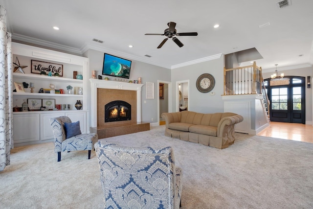 living room featuring a glass covered fireplace, light carpet, crown molding, and visible vents