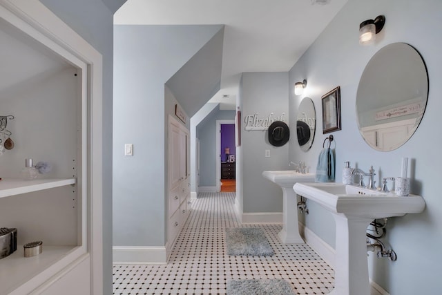 full bathroom featuring two sinks and baseboards