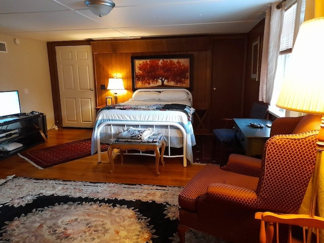 bedroom with hardwood / wood-style flooring and wood walls