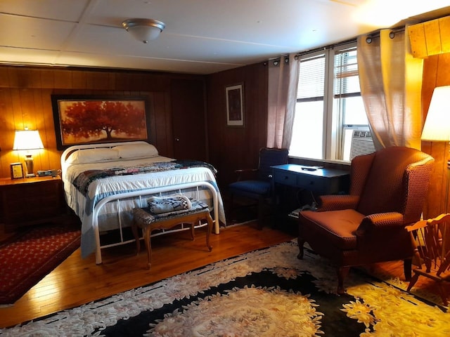 bedroom with hardwood / wood-style flooring, wooden walls, and cooling unit