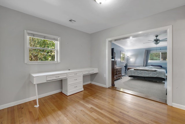 bedroom featuring light hardwood / wood-style floors, built in desk, and crown molding