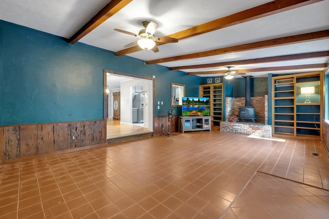 unfurnished living room featuring tile patterned floors, a wood stove, and ceiling fan