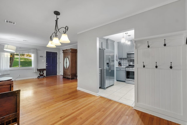 kitchen with light hardwood / wood-style flooring, gray cabinets, appliances with stainless steel finishes, tasteful backsplash, and decorative light fixtures