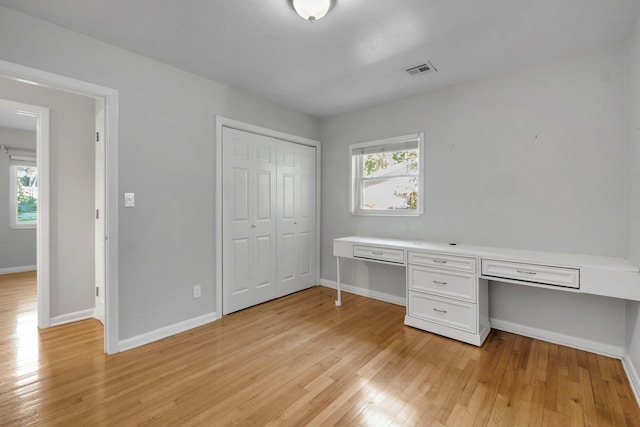 unfurnished office with light wood-type flooring and built in desk