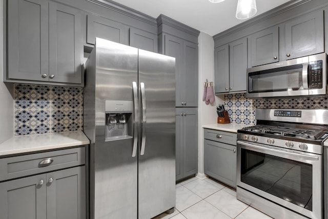 kitchen featuring gray cabinets, light tile patterned floors, stainless steel appliances, and tasteful backsplash