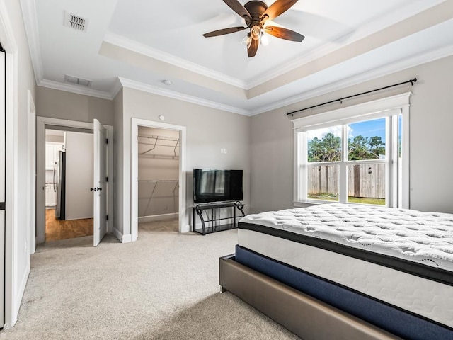 2288 Wabash Trl, Tallahassee, FL 32303 - carpeted bedroom featuring a tray ceiling, ornamental molding, a walk in closet, freestanding refrigerator, and ceiling fan