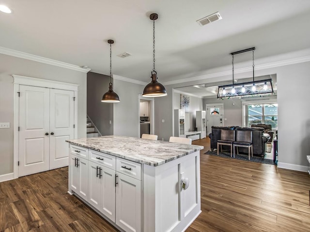 2288 Wabash Trl, Tallahassee, FL 32303 - kitchen with crown molding, white cabinets, a center island, dark wood-style flooring, and light stone counters