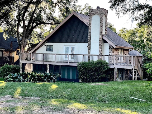 back of property featuring a wooden deck and a lawn