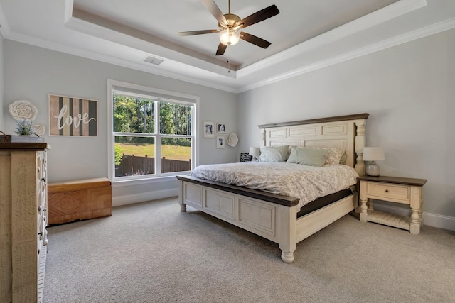 carpeted bedroom featuring ceiling fan, a raised ceiling, and crown molding