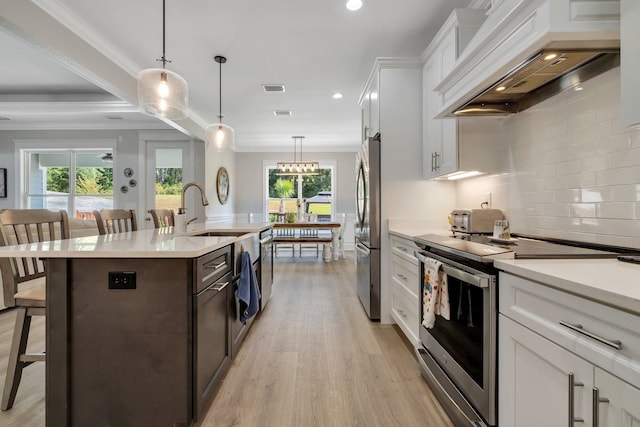 kitchen featuring white cabinets, stainless steel appliances, premium range hood, and a breakfast bar area