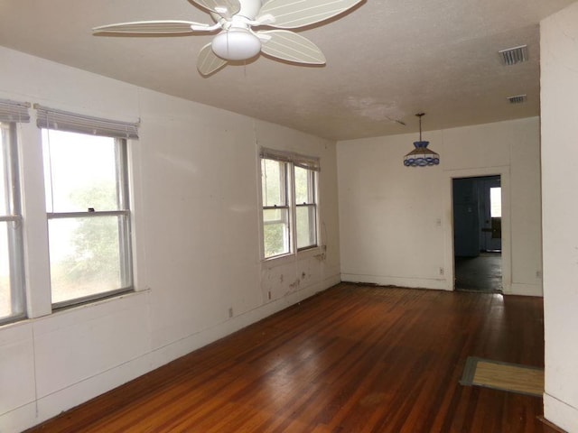 unfurnished room with ceiling fan, dark wood-type flooring, and a healthy amount of sunlight