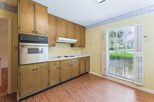 711 Kenilworth Rd, Tallahassee, FL 32312 - kitchen with oven, under cabinet range hood, light countertops, brown cabinets, and light wood-style flooring