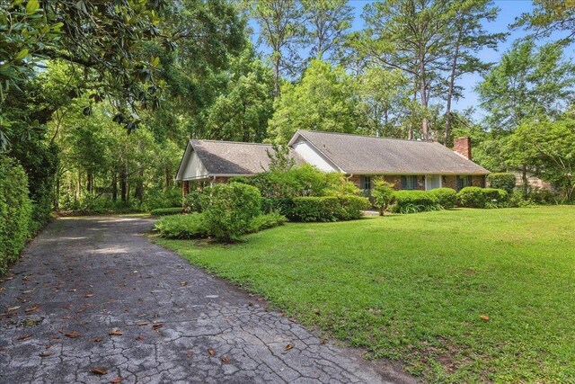 711 Kenilworth Rd, Tallahassee, FL 32312 - view of front of house featuring a front lawn, a chimney, and driveway