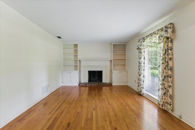711 Kenilworth Rd, Tallahassee, FL 32312 - unfurnished living room with wood finished floors, built in shelves, and a brick fireplace
