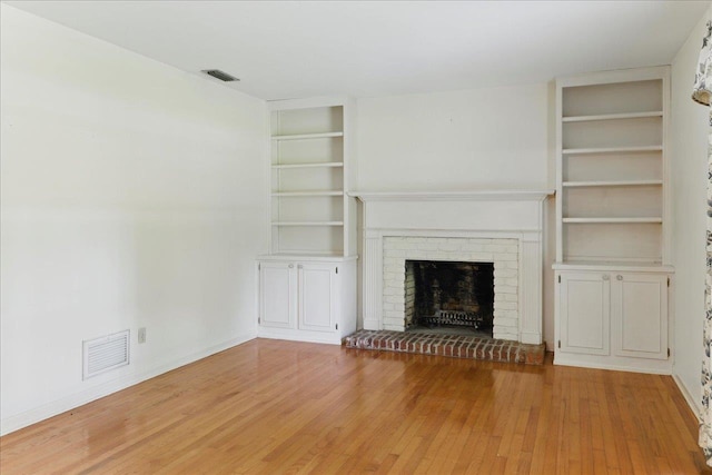 711 Kenilworth Rd, Tallahassee, FL 32312 - unfurnished living room featuring light wood finished floors, built in shelves, and a brick fireplace