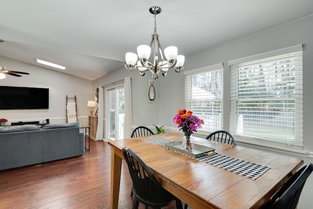 dining room with dark wood-type flooring, lofted ceiling, ceiling fan with notable chandelier, and plenty of natural light