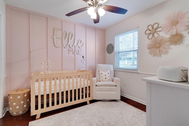 bedroom featuring wood-type flooring, a nursery area, and ceiling fan