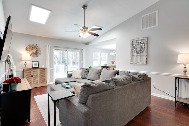 living room with ceiling fan with notable chandelier, vaulted ceiling, and dark hardwood / wood-style floors