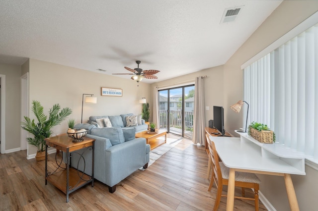 285 Payne Street 23B, Walton Beaches, FL 32550 - living room with light wood finished floors, baseboards, ceiling fan, and a textured ceiling