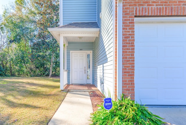 entrance to property featuring a garage and a yard