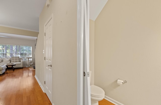 bathroom featuring vaulted ceiling, ornamental molding, toilet, and hardwood / wood-style floors