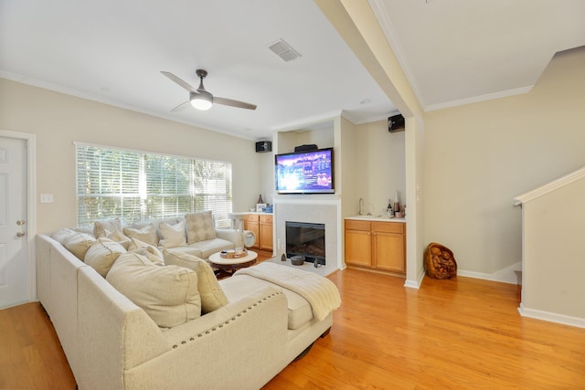 living room featuring ornamental molding, ceiling fan, and light wood-type flooring